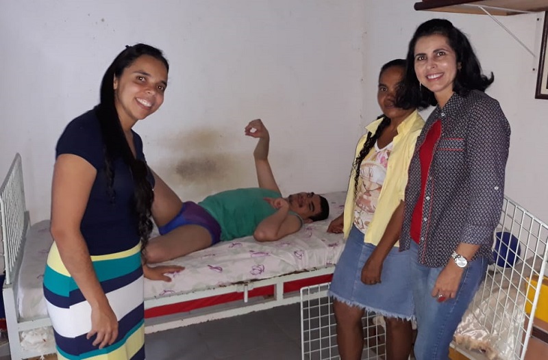 Professoras Joana Cristina Neves de Menezes Faria e Yane Ondina de Almeida em visita ao jovem Alex e à sua mãe Ilza, no momento da doação de parte da arrecadação do Bazar da Modelagem 